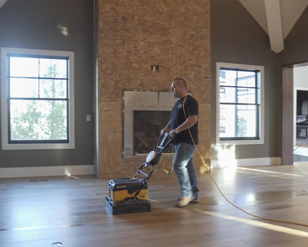 Man adding maintenance (or screen and recoat) coat to wood flooring.
