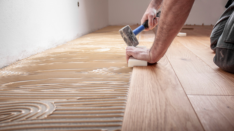 Man installing hardwood flooring over ceramic tile.