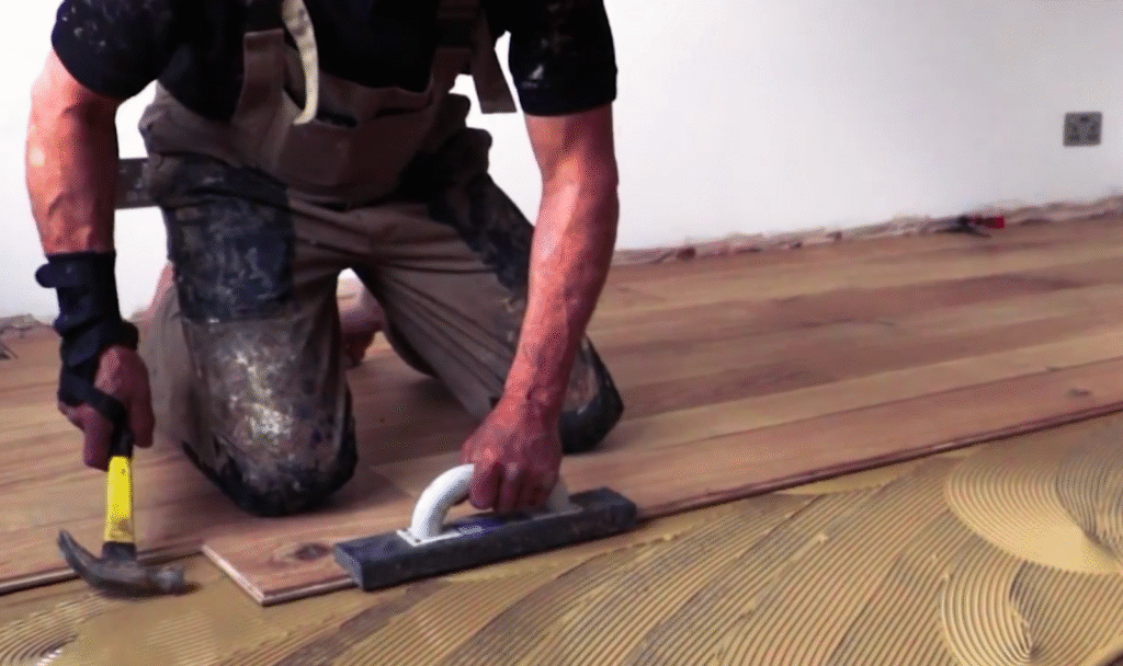 Man installign hardwood floor over concrete with glue-down method.